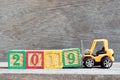 Toy forklift hold letter block 9 to word 2019 on wood background Royalty Free Stock Photo