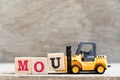 Toy forklift hold letter u in word mou abbreviation of memorandum of understanding on wood background