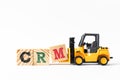 Toy forklift hold wood block M to complete word CRM Abbreviation of Customer Relationship Management on white background