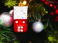 A toy in the form of a red house hangs on a Christmas tree. Christmas tree decoration in the form of a winter house hanging on a Royalty Free Stock Photo