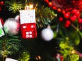 A toy in the form of a red house hangs on a Christmas tree. Christmas tree decoration in the form of a winter house hanging on a Royalty Free Stock Photo
