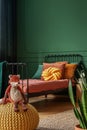 Toy fox on a yellow pouf in a real photo of a kid bedroom with green walls and orange sheets