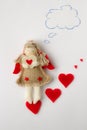 Toy girl angel holds a valentine in his hands and thinks about her lover on a white background Royalty Free Stock Photo