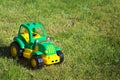 Toy green-yellow tractor on the grass.