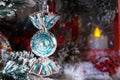 Toy hanging on a branch of a Christmas tree against a red lantern with a candle Royalty Free Stock Photo