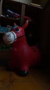 toy horse is red in color, with a dirty patch stuck to the head, dark blurred background