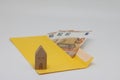 Toy house. banknotes in a yellow envelope. open envelope with banknotes on a light background. envelope with banknotes