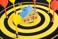 Toy house in the center of the darts board amid darts. The concept of setting targets and trying to reach them. Royalty Free Stock Photo