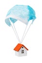 A toy house is flying on a parachute from a medical mask, isolated on a white background. Quarantine exit concept Royalty Free Stock Photo