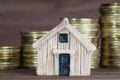 Toy house model against coins stacks background Royalty Free Stock Photo