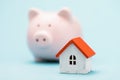 Toy house and piggy bank on a blue background. The concept of saving money for your home Royalty Free Stock Photo