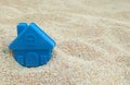 Toy house submerged in white sand