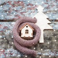 Toy house is wrapped in a warm scarf, it`s snowing. in the backg Royalty Free Stock Photo