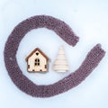 Toy house is wrapped in a warm scarf, it`s snowing. in the backg Royalty Free Stock Photo