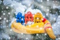 Toy houses is wrapped in a warm scarf, it`s snowing on a natural natural background of a real fir in the snow, toned. Royalty Free Stock Photo