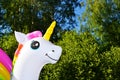 Toy inflatable unicorn on a background of green trees