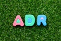 Toy letter in word ADR Abbreviation of Adverse drug reaction on green grass background