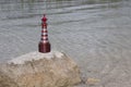 A toy lighthouse stands on a stone, lit by the sun Royalty Free Stock Photo