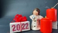 Toy little angel, red burning candles and white gift box with 2022 text. Royalty Free Stock Photo