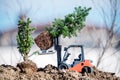 A toy loader loads and plants small coniferous trees in the ground. Royalty Free Stock Photo