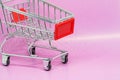 Toy metal shopping cart or trolley on gradient pink background with copy space Royalty Free Stock Photo