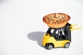 A toy miniature yellow forklift carries a baked cake to a birthday boy. Machine on a white background. Close-up. Free space for