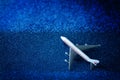 Toy model of a passenger plane - airliner on a sparkling blue background. Simulation of flight in the sky. Relocation, vacation or