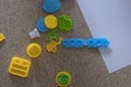 Toy molds for use with yellow and green blue plasticine. Children toys on the floor with green clay