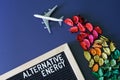 Toy passenger airliner with a contrail of multi-colored flower petals next to the inscription alternative energy. Concept of eco-