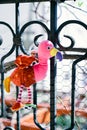 Toy pink flamingo hangs on a metal balcony railing. Close-up