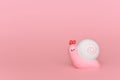 Toy pink snail with a white shell carapace on a pink background.