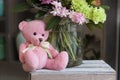 Toy pink Teddy bear sitting on a wooden box Royalty Free Stock Photo