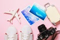 Toy plane, camera, shoes and photos on a pink background, top view