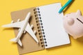 Toy plane, notebook and piggy bank on a yellow background. Concept on saving money on flights Royalty Free Stock Photo