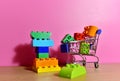 Toy plastic bricks in shopping cart for kids. Plastic construction blocks for children play. Colorful building block in basket Royalty Free Stock Photo