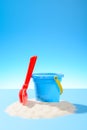 Toy plastic bucket and shovel in the sand. Blue background with copy space Royalty Free Stock Photo