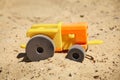 A toy plastic tractor on the sand of a playground.