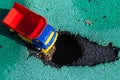 Toy plastic truck with a red body stopped in front of the pit. The car can not go. Hole on asphalt. The road needs Royalty Free Stock Photo