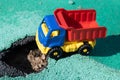 Toy plastic truck with a red body stopped in front of the pit. The car can not go. Hole on asphalt. The road needs Royalty Free Stock Photo