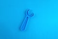 Toy plastic wrench of blue color on a blue background.
