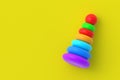 Toy pyramid tower on yellow background. Children education. Educational games. Preschool development. Copy space