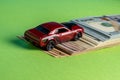 Toy red car drives up a hill of dollar bills Royalty Free Stock Photo