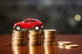 Toy red car top of a stack of coins on a table with bokeh background Royalty Free Stock Photo