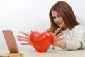 Toy red heart. Girl holds her heart in front of phone screen. Talking on Internet. Valentines Day, communication by videoconferen