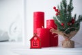 Toy red winter house in home festive interior with Christmas candles and white wall on background Royalty Free Stock Photo