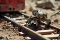 A toy robot is photographed while sitting on a train track, A brick laying robot in action on a sunny day, AI Generated