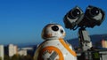 Toy robots Sphero Star Wars BB8 and Disney Pixar Wall-E standing in front of blurry cityscape in background