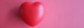 Toy rubber heart lying on red background closeup top view