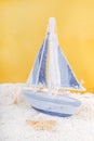 Toy sailing boat and seashells on yellow background Royalty Free Stock Photo