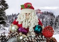 Toy Santa Claus with Christmas decorations on the background of a winter landscape with a snow-covered forest in the mountains and Royalty Free Stock Photo